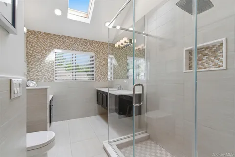 a bathroom with a bathtub shower sink mirror and toilet