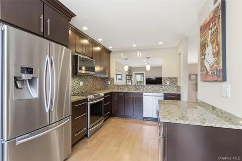 a kitchen with stainless steel appliances granite countertop a refrigerator a stove and a sink with wooden floor