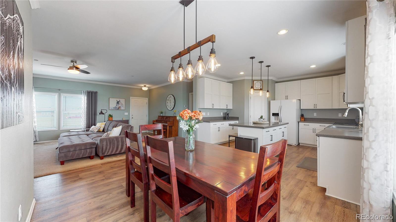 4038 Meadowlark Road Fort Lupton, CO 80621 - Photo 13 of 40 a view of a dining room and livingroom with furniture wooden floor a chandelier