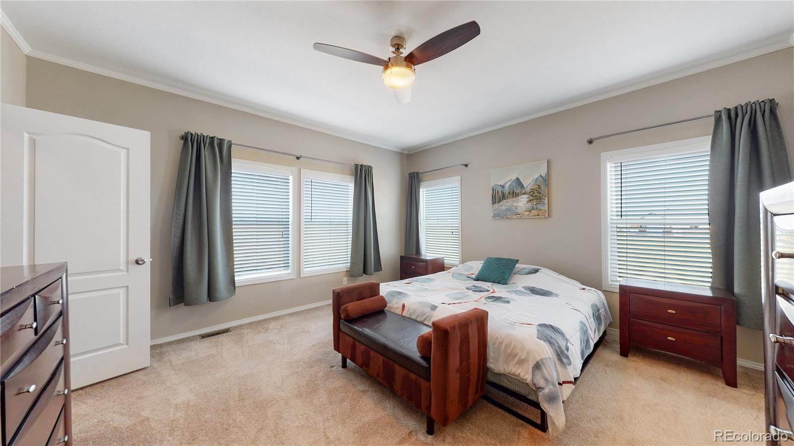 4038 Meadowlark Road Fort Lupton, CO 80621 - Photo 24 of 40 a spacious bedroom with a bed a window and a chandelier