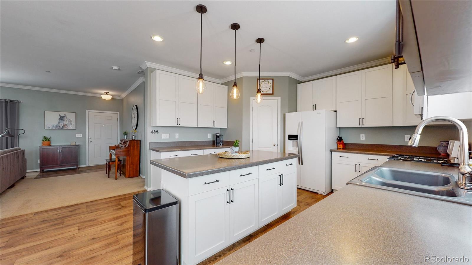 4038 Meadowlark Road Fort Lupton, CO 80621 - Photo 7 of 40 a kitchen with stainless steel appliances a stove a sink a refrigerator and white cabinets with wooden floor