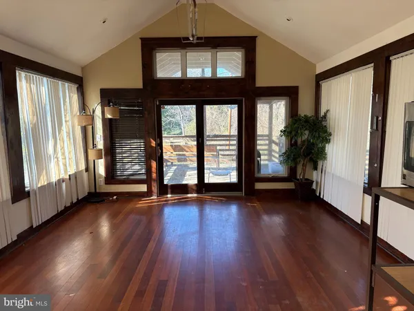 an empty room with wooden floor and windows
