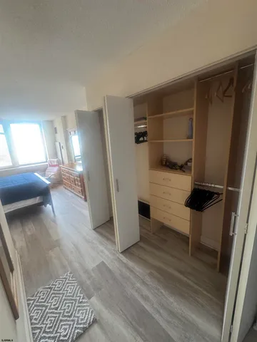 a view of a hallway to a livingroom with wooden floor and furniture