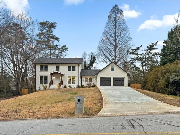 a view of a house with a yard and large tree
