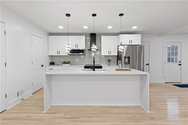 a view of kitchen with stainless steel appliances kitchen island sink refrigerator and cabinets