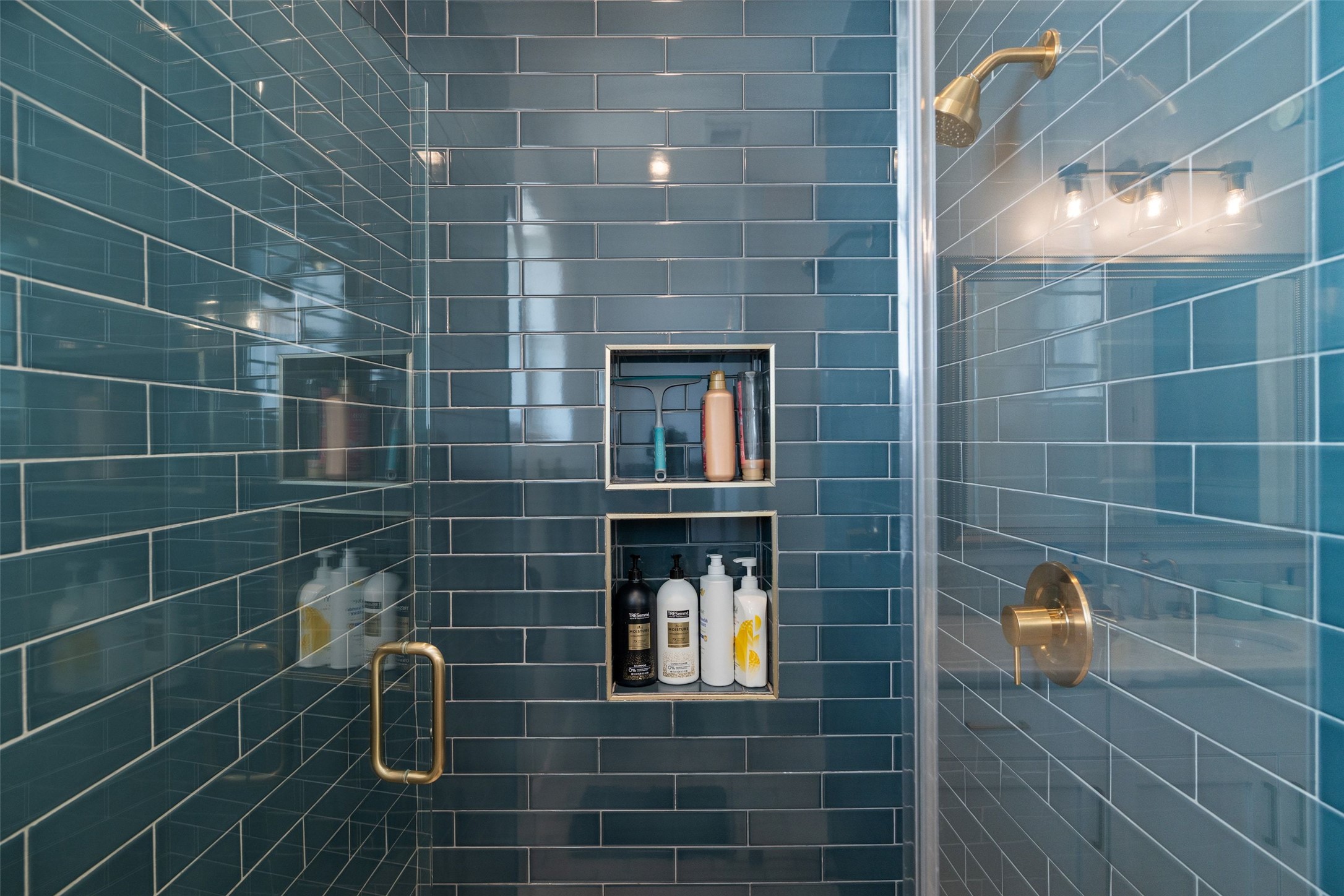 810 Kothmann Road Dripping Springs, TX 78620 - Photo 21 of 40 Glazed subway tiles line a walk-in shower featuring gold-toned fixtures and built-in niches.