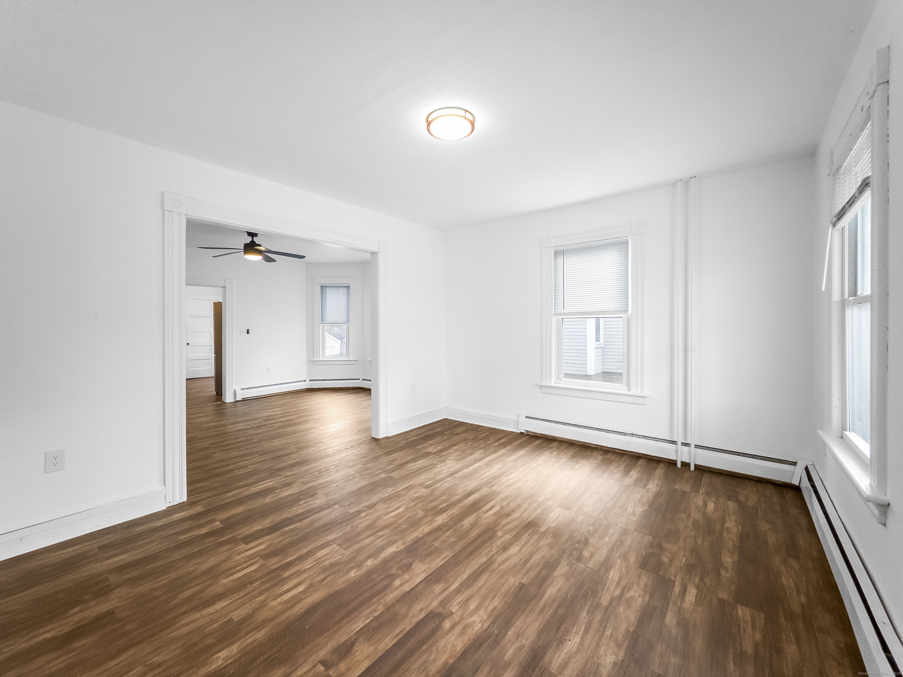 an empty room with wooden floor and windows