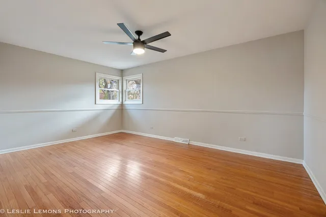 an empty room with wooden floor fan and windows