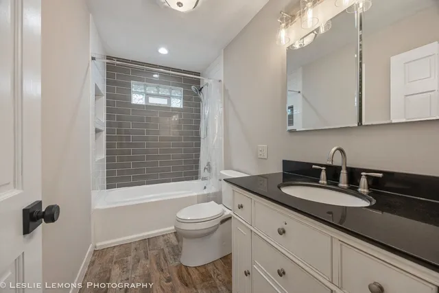 a bathroom with a granite countertop sink a toilet a mirror and shower
