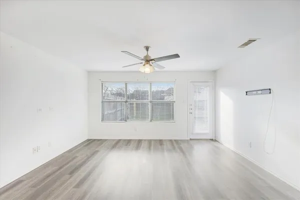 an empty room with wooden floor and windows