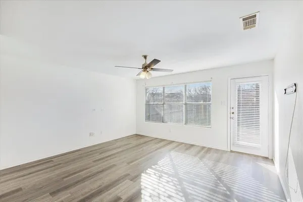a view of empty room with wooden floor and fan