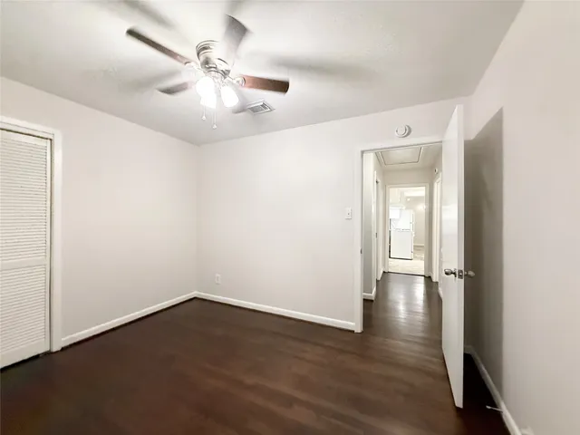 an empty room with wooden floor and fan