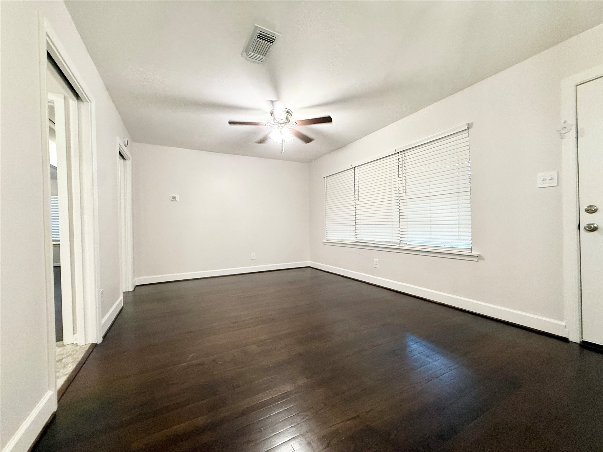 913 Wimberly Street Angleton, TX 77515 - Photo 3 of 24 an empty room with wooden floor chandelier fan and windows