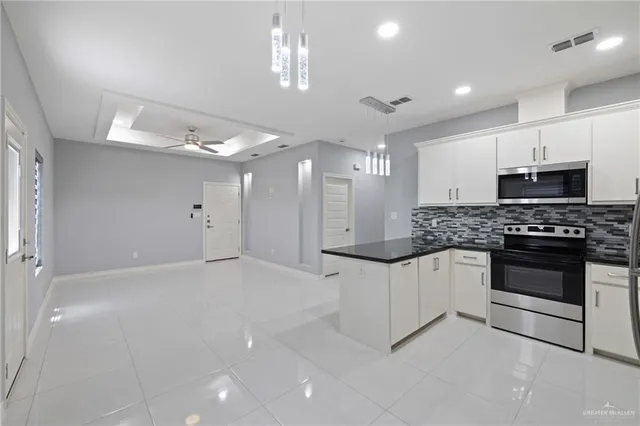 a kitchen with granite countertop a white stove top oven and cabinets