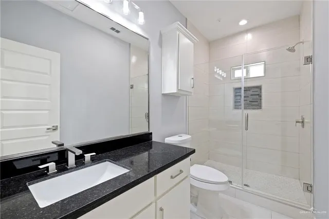 a bathroom with a granite countertop sink toilet and shower