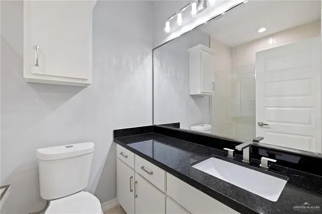 a bathroom with a granite countertop sink a toilet and a mirror