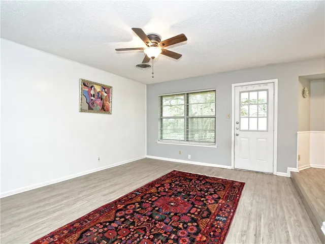 an empty room with wooden floor a ceiling fan and windows