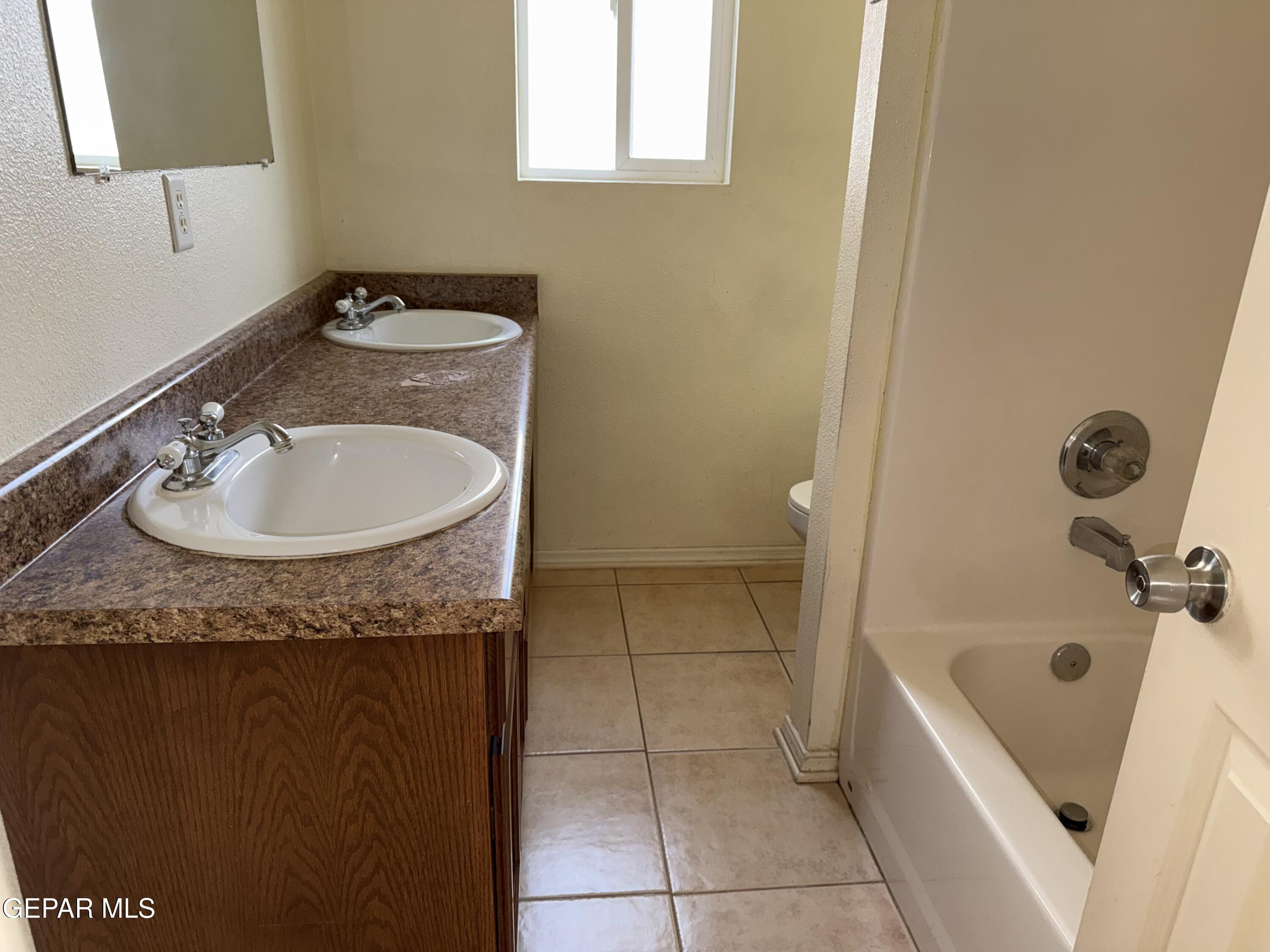 456 Passmore Road Socorro, TX 79927 - Photo 15 of 23 a bathroom with a granite countertop sink a toilet and bathtub