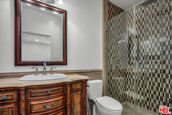 a bathroom with a granite countertop toilet sink and mirror
