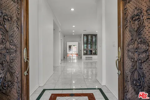 a view of a hallway with a dining table and chandelier