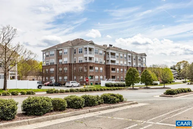 a front view of a building with street view and trees