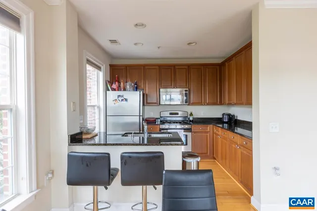 a kitchen with stainless steel appliances granite countertop a stove a refrigerator a sink dishwasher and white cabinets with wooden floor