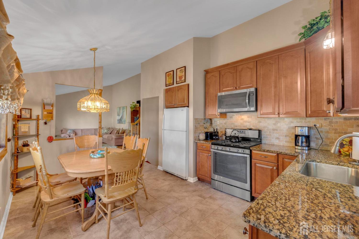 77 Albemarle Road Colonia, NJ 07067 - Photo 13 of 30 a kitchen with a dining table chairs stainless steel appliances and cabinets