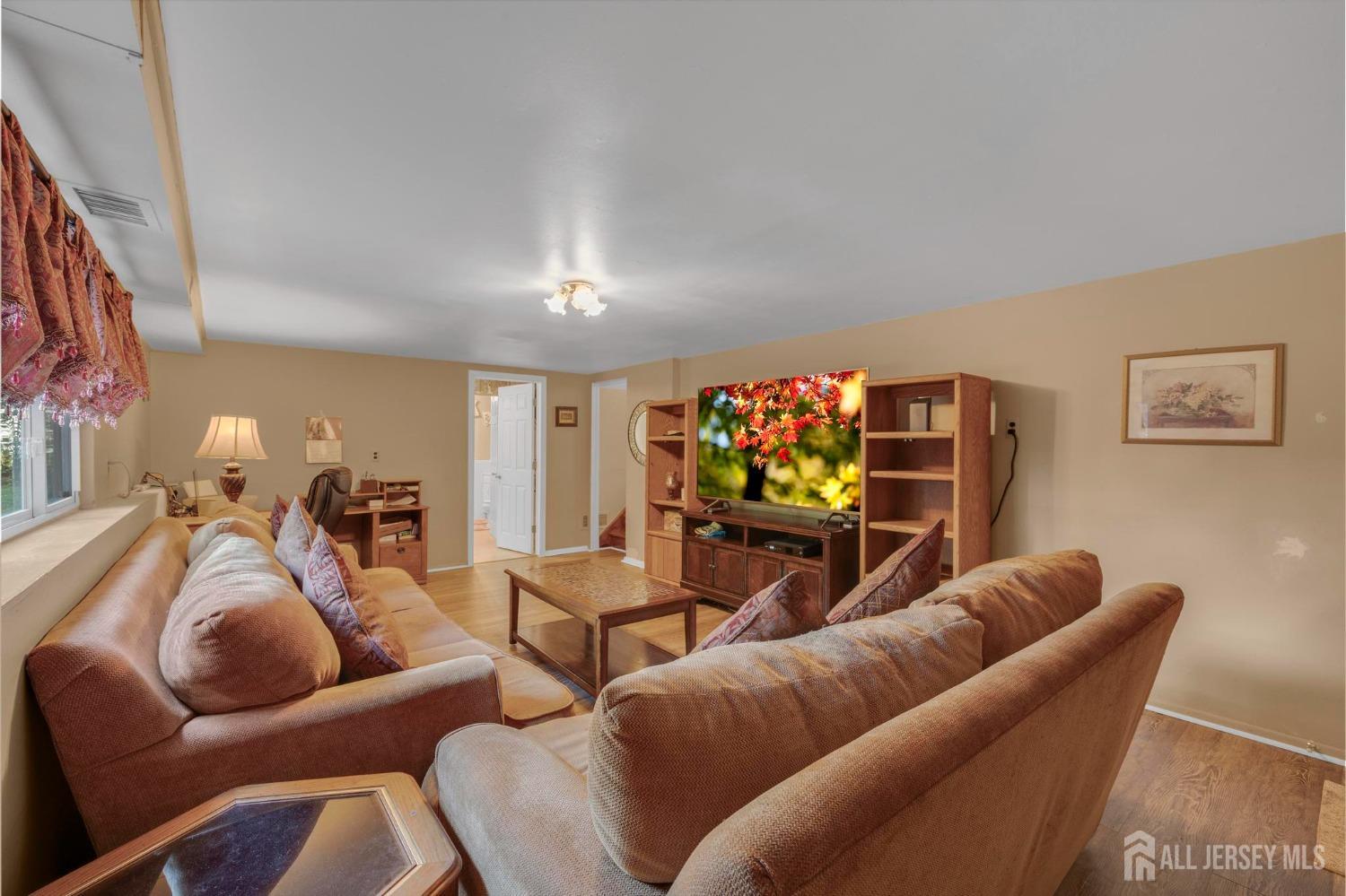 77 Albemarle Road Colonia, NJ 07067 - Photo 22 of 30 a living room with furniture a flat screen tv and a couch