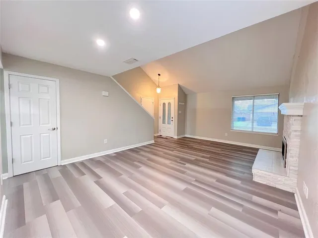 a view of a livingroom with wooden floor and a fireplace