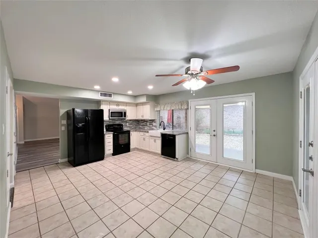 a large kitchen with granite countertop a sink and white cabinets
