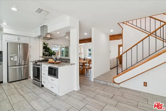 a kitchen with stainless steel appliances kitchen island granite countertop a refrigerator a stove a sink and a microwave