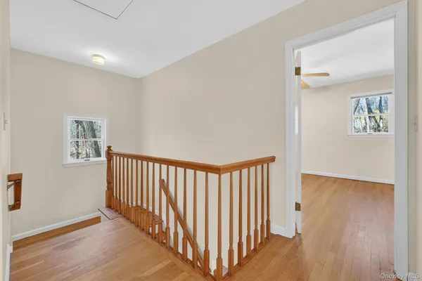 a view of a hallway with entryway to wooden floor and staircase