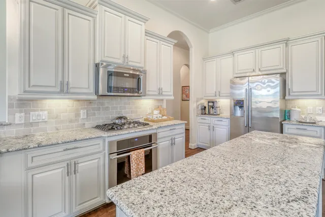a kitchen with granite countertop a refrigerator and cabinets
