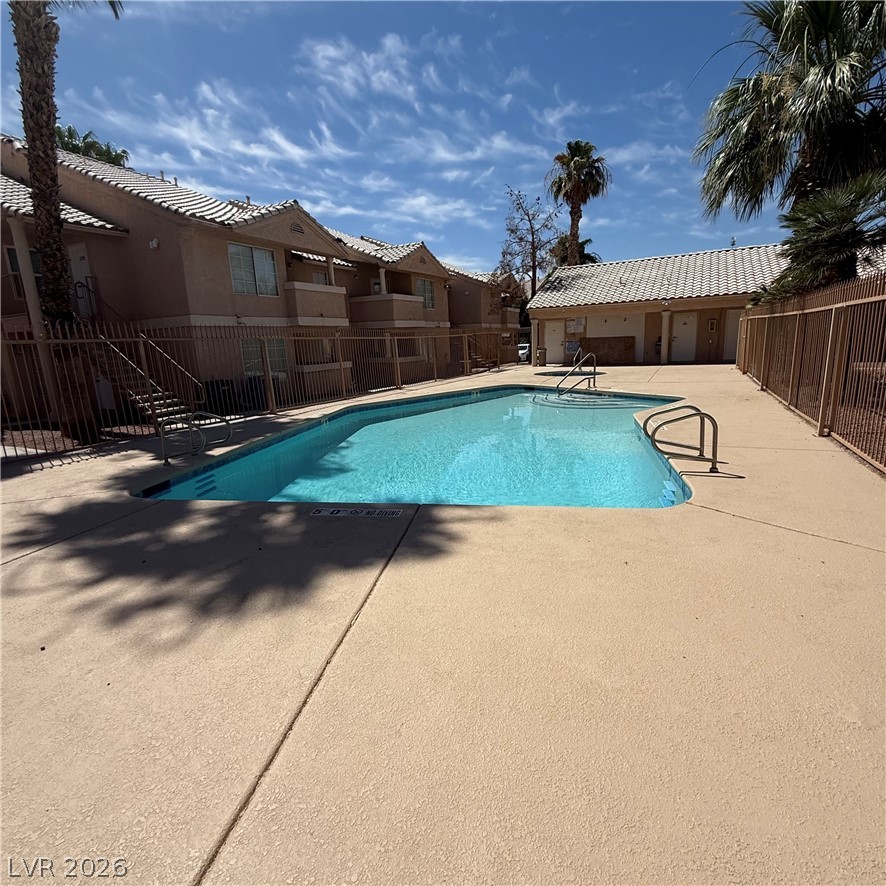 1830 North Pecos Road, Unit 258 Las Vegas, NV 89115 - Photo 4 of 14 An inviting community pool with ample patio space is surrounded by palm trees and residential buildings.