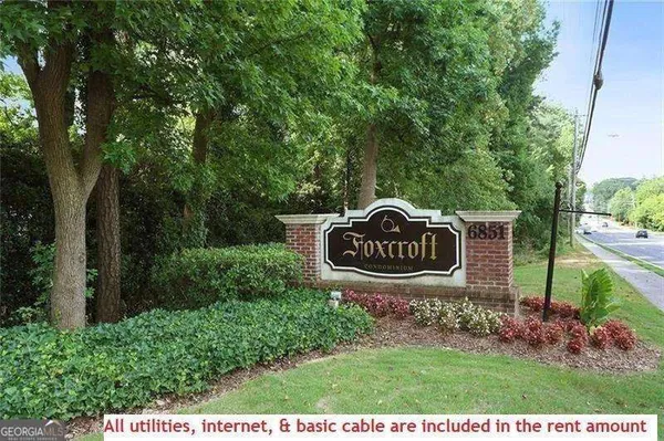 a view of a sign in a yard with large trees