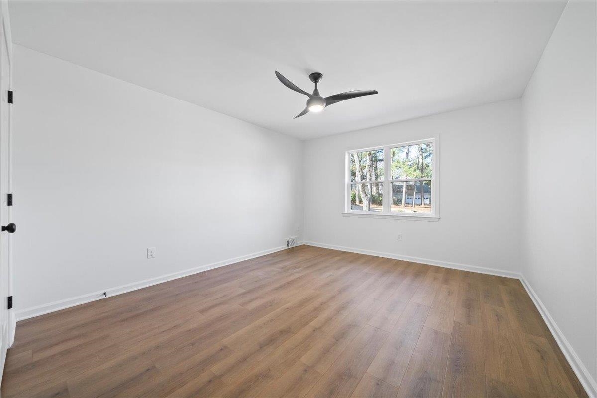 1676 Miller Farms Road Germantown, TN 38138 - Photo 16 of 37 Spacious interior room featuring wood-finish flooring, a contemporary ceiling fan with integrated lighting, a large window, white walls, and white baseboards