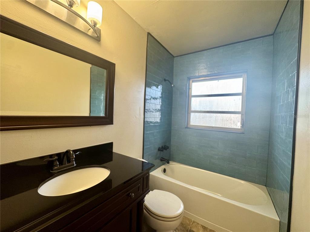 1516 Hawk Griffin Road Plant City, FL 33563 - Photo 14 of 17 a bathroom with a granite countertop sink toilet a mirror and bathtub