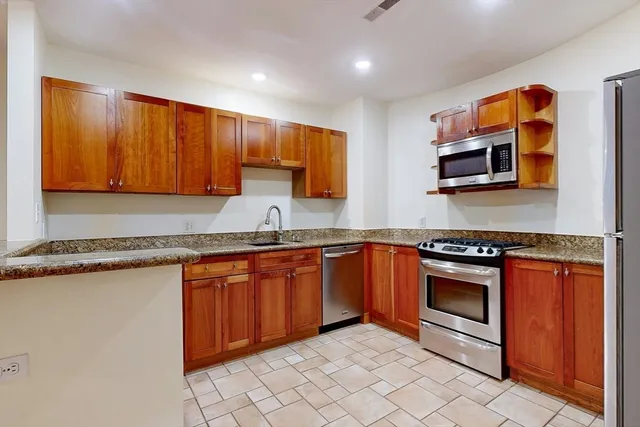 a kitchen with stainless steel appliances granite countertop a stove a sink and a microwave