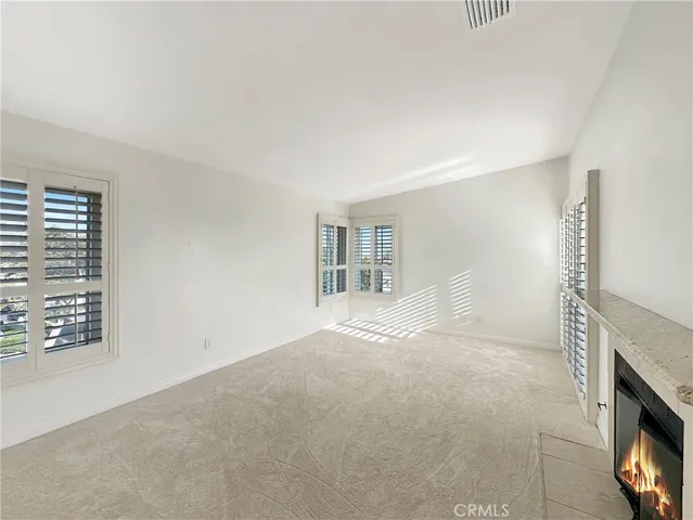 a view of an empty room with a fireplace and a window