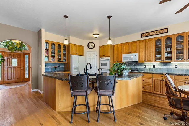 a kitchen with stainless steel appliances granite countertop wooden floor a stove a sink dishwasher and cabinets with wooden floor