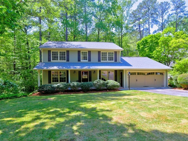 a view of a house with a yard potted plants and a bench