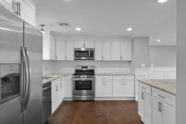 a kitchen with granite countertop white cabinets stainless steel appliances and a sink