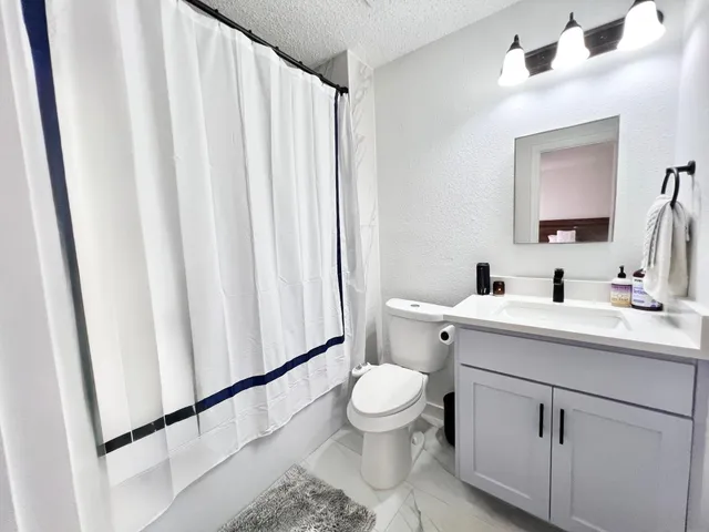 a bathroom with a sink a toilet and shower