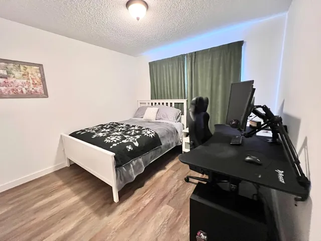 a bed sitting in a bedroom next to a window with wooden floor