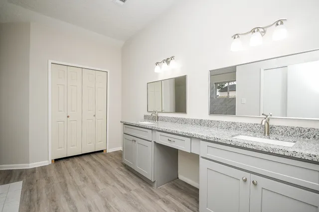 a bathroom with a granite countertop sink a mirror and shower