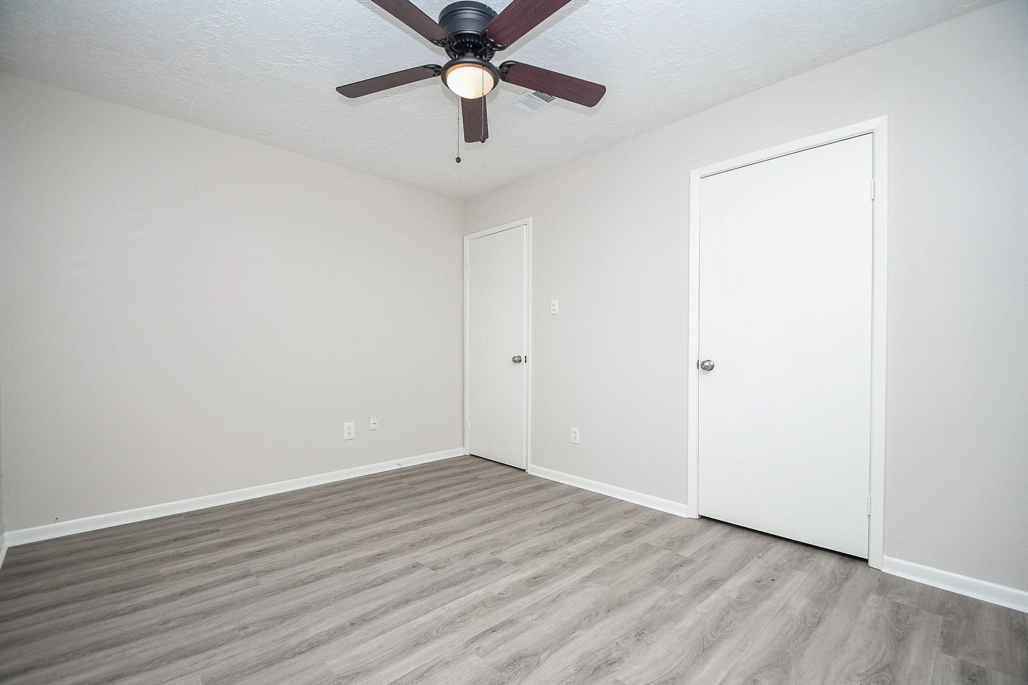 15315 Cedar Ridge Drive Houston, TX 77082 - Photo 15 of 20 an empty room with wooden floor and ceiling fan