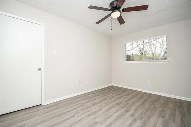 an empty room with wooden floor and a ceiling fan