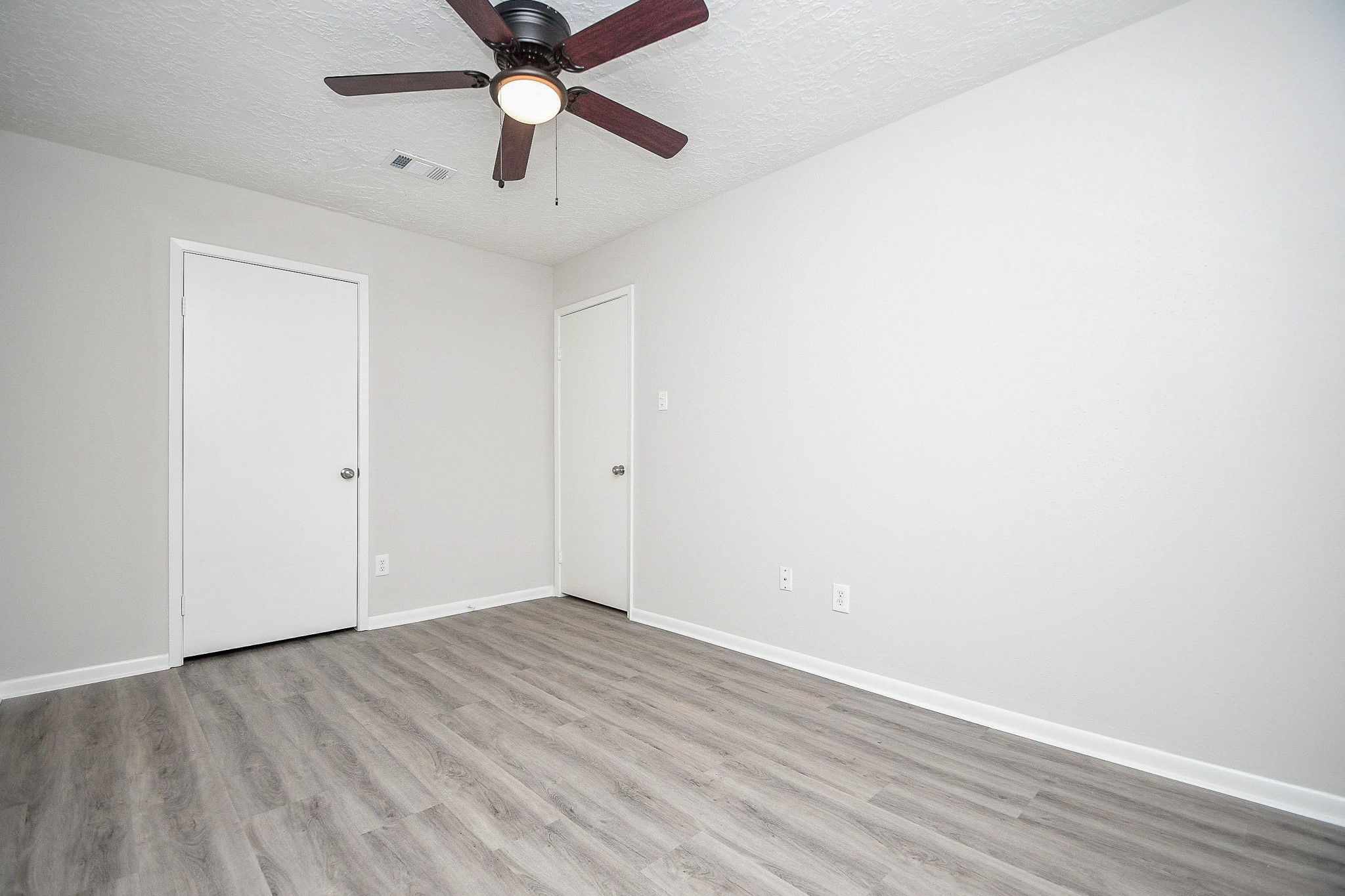 15315 Cedar Ridge Drive Houston, TX 77082 - Photo 18 of 20 an empty room with wooden floor and a ceiling fan