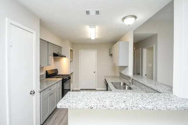 a large kitchen with kitchen island granite countertop a sink stove and refrigerator