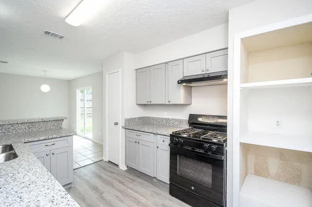 a kitchen with granite countertop a sink stove and cabinets